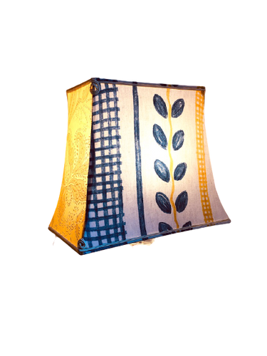 Un abat-jour pagode rectangle recouvert d'un tissu de coton au motif graphique sur les grandes faces et d'un voile de coton teint en jaune sur les petites.
